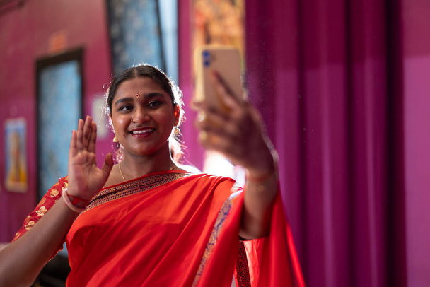 Twee vrolijke jonge Indianen in traditionele outfits nemen een selfie, presenteren hun culturele kleding. - Foto, afbeelding