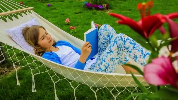 Chica leyendo un libro en una hamaca en el jardín
 - Imágenes, Vídeo