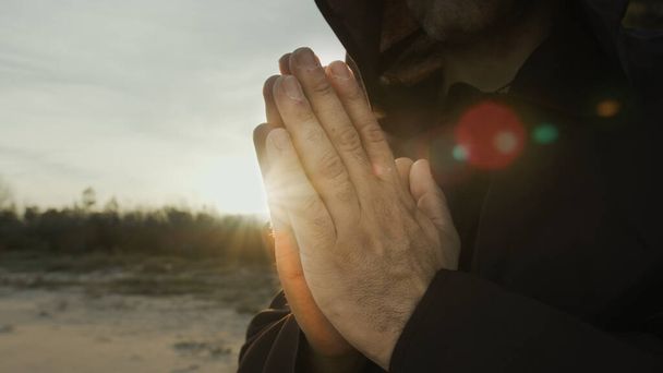 Mãos de um monge orando ao pôr do sol na natureza do campo. - Foto, Imagem
