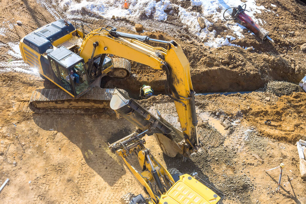 建設現場でアースモービング作業中,掘削機がトレンチを掘る - 写真・画像