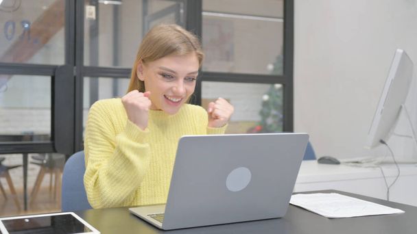 Podekscytowana młoda blondynka świętuje sukces na laptopie - Zdjęcie, obraz
