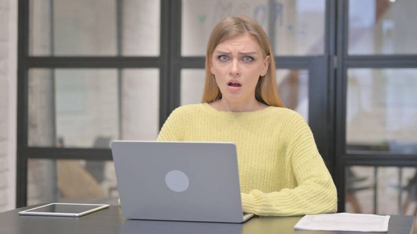 Lässige kreative Frau, die bei der Arbeit am Laptop in die Kamera schaut, mag es nicht - Foto, Bild