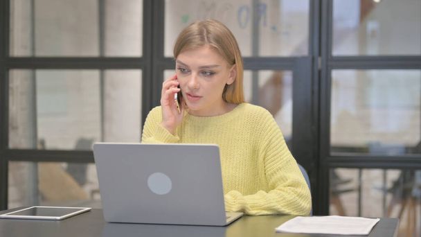 Niezobowiązująca kobieta kreatywna rozmawiająca przez telefon w pracy - Zdjęcie, obraz