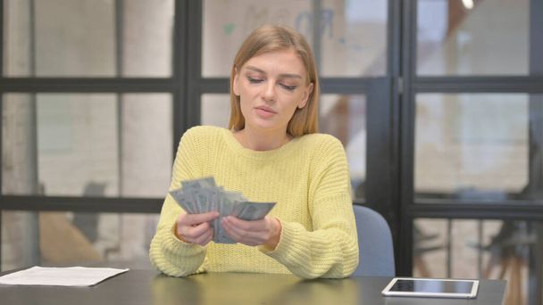 Glückliche lässige kreative Frau beim Geldzählen im Amt - Foto, Bild