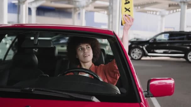Χαμογελώντας Αφρο-Αμερικανός γυναίκα οδηγός ταξί περιμένει στο αυτοκίνητο, ενώ βάζοντας κίτρινη πινακίδα ταξί στην οροφή. Παιδιά, η έννοια της υπηρεσίας. Αργή κίνηση - Πλάνα, βίντεο