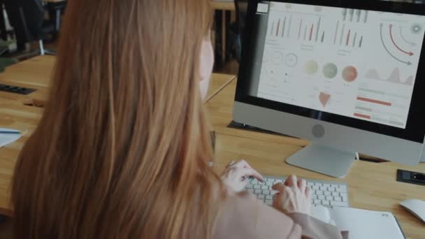 Přes rameno záběr podnikatelky psaní na bezdrátové počítačové klávesnici při práci na finanční zprávu na kancelářském stole - Záběry, video