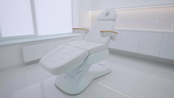 Białe krzesło kosmetologiczne z elementami drewnianymi we wnętrzu kliniki, bez osób. - Materiał filmowy, wideo