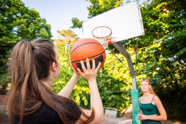 Dziewczyna trzyma koszykówkę i strzela podczas gry. - Zdjęcie, obraz