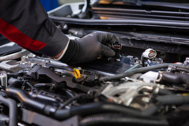 the car mechanic makes diagnostics of the car in the engine. car service and audit by an employee in a large car service. candle replacement  - Photo, Image