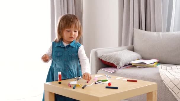 Gyerekfejlesztés. Egy lány papírból és ragasztóból készít kézművességet. Színes ceruzák - Felvétel, videó