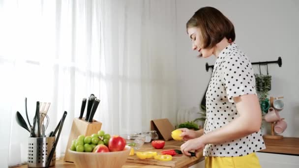 Atraktivní bělošská máma krájí čerstvou zeleninu na salát. Šťastná energická chytrá matka pracující v moderní kuchyni a vařící zdravé jídlo k snídani. Koncept přípravy jídla. Pedagogika. - Záběry, video