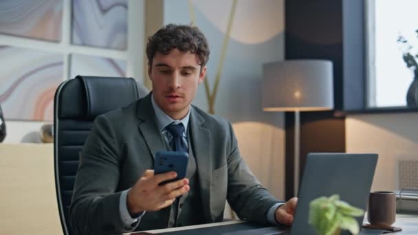 Happy employee picking up smartphone answering call at buro closeup. Man professional talking mobile phone enjoying conversation in light office. Smiling businessman working at desk. Corporate people  - Footage, Video