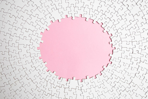 Plain white jigsaw puzzle  on pink  color background, oval shaped frame  - Photo, Image