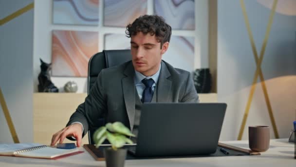 Stressed businessman looking mobile phone at work desk with laptop closeup. Nervous man manager feeling irritated having business fail at workplace. Annoyed guy reading cellphone gesturing emotionally - Footage, Video