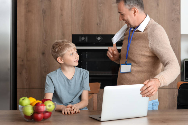 Зрілий лікар з ноутбуком і його маленький син на кухні - Фото, зображення