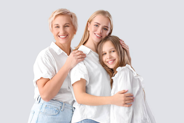 Little girl with her mom and grandmother hugging on light background - Photo, Image