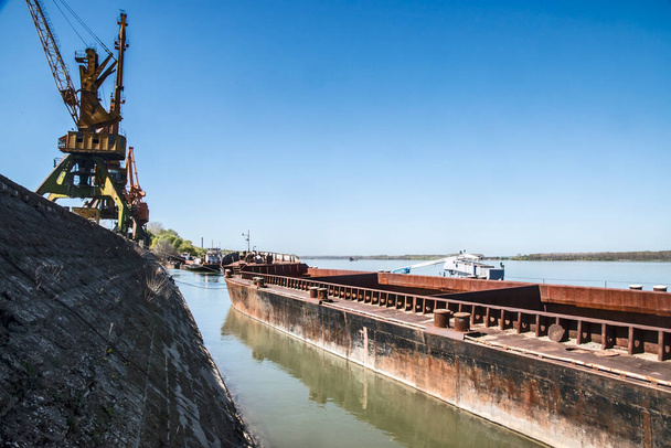 晴れた日の川港でバルク貨物バージと産業クレーン - 写真・画像