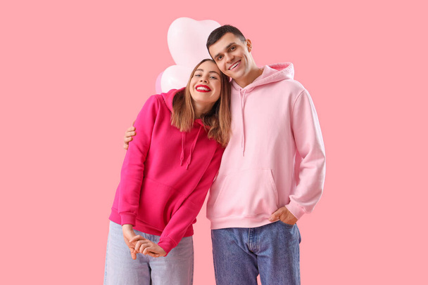 Young couple in love with balloons hugging on pink background. Valentine's Day celebration - Photo, Image