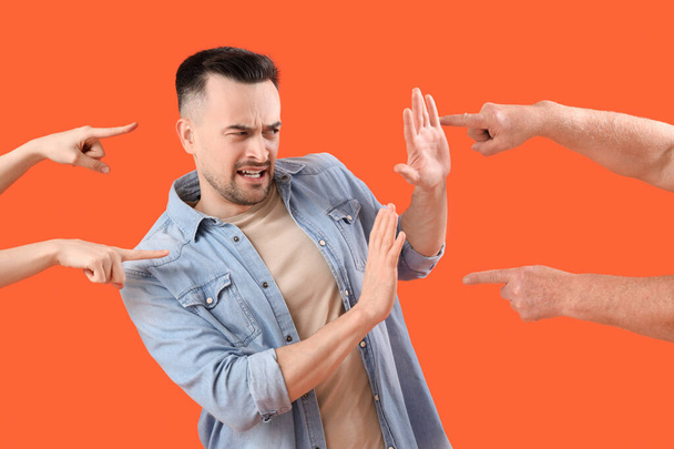 People pointing at young man on orange background. Accusation concept - Photo, Image