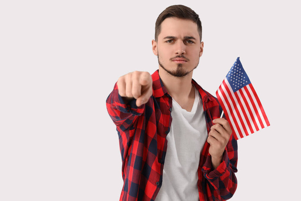 Νεαρός με σημαία ΗΠΑ δείχνει θεατή σε λευκό φόντο. Έννοια της επίκλησης - Φωτογραφία, εικόνα