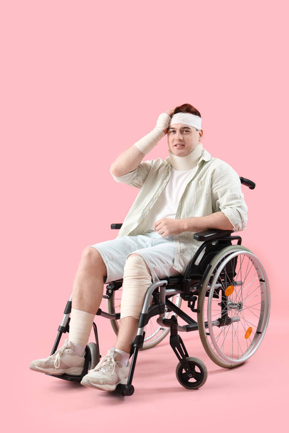 Joven lesionado después de accidente en silla de ruedas sobre fondo rosa - Foto, Imagen