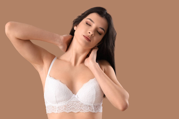 Beautiful young woman in white lace bra on brown background - Photo, Image