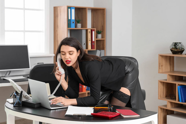 Atractiva secretaria hablando por teléfono en la oficina - Foto, imagen