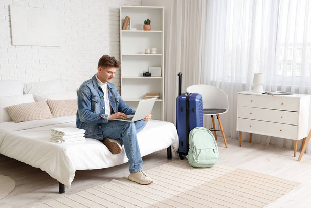Muž turista pomocí notebooku na posteli v hotelovém pokoji - Fotografie, Obrázek