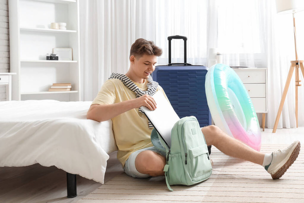 Touriste masculin prenant ordinateur portable à partir du sac à dos dans la chambre d'hôtel - Photo, image