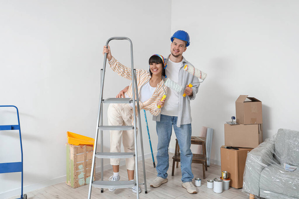 Молодая пара с роллерами и стремянками во время ремонта в своем новом доме - Фото, изображение