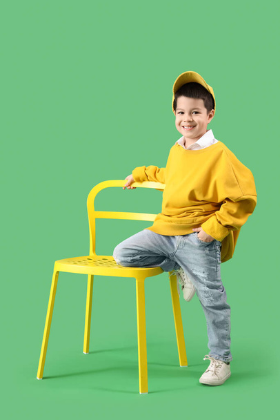 Roztomilý malý asijský chlapec v dospělé oblečení s židlí na zeleném pozadí - Fotografie, Obrázek