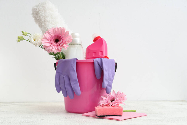 Balde com suprimentos de limpeza, ferramentas e flores de primavera em fundo branco - Foto, Imagem