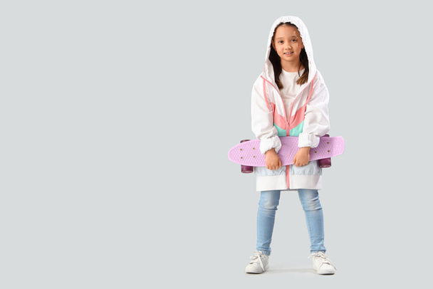 Portrait of fashionable little girl with skateboard on white background - Фото, изображение
