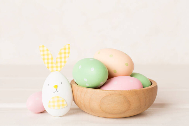 Huevos coloridos de Pascua en tazón sobre mesa de madera - Foto, Imagen