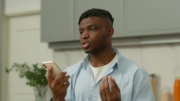 Vakava Afrikkalainen amerikkalainen mies etninen kaveri mies tallentaa ääniviestin vastaajaan puhua matkapuhelin kaiutin tallennus vastaus sosiaalisen median älypuhelin puhuu kovaa matkapuhelin mikrofoni kotona - Materiaali, video