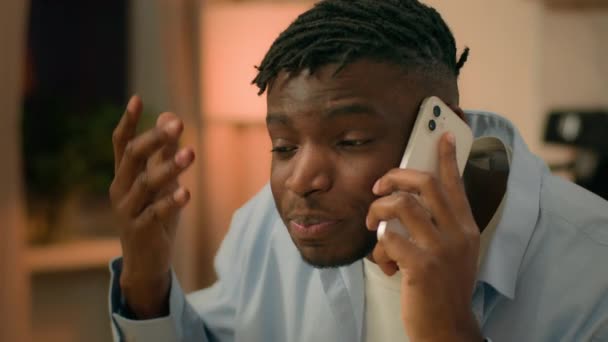 Dühös őrült dühös agresszív stresszes férfi afro-amerikai férfi srác este otthon vitatkozni konfliktus beszél mobiltelefon probléma rossz kapcsolat stressz kiabálás kiabálás kiabálás veszekedés - Felvétel, videó