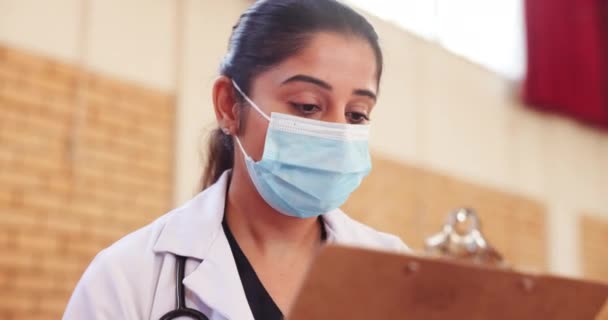 Doctor, clipboard or mask in vaccination, consultation or question of compliance, health insurance. Woman, physician or paperwork in communication, risk or advice as healthcare services in hospital. - Footage, Video