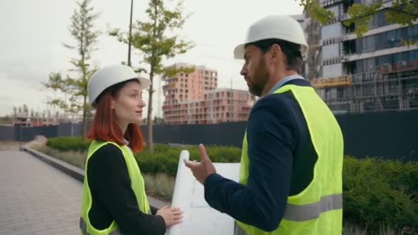 İki müteahhit inşaat mühendisi, şehir binalarını işaret eden takım çalışmasını tartışıyor. İşbirliği yapan inşaat işçilerini kentsel kalkınma planıyla işaret ediyorlar. - Video, Çekim