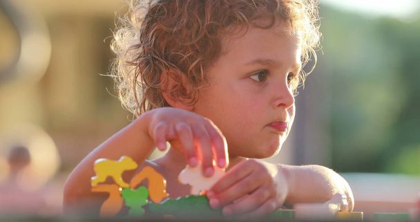 Child learning to play with puzzle pieces in deep concentration, focusing, and frustration - 写真・画像