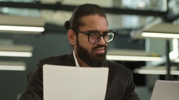 Arabo uomo d'affari musulmano imprenditore indiano imprenditore datore di lavoro confuso con documenti e laptop in ufficio problemi burocratici cattivo risultato parlando videochiamata lavorare con i documenti fallimento - Filmati, video