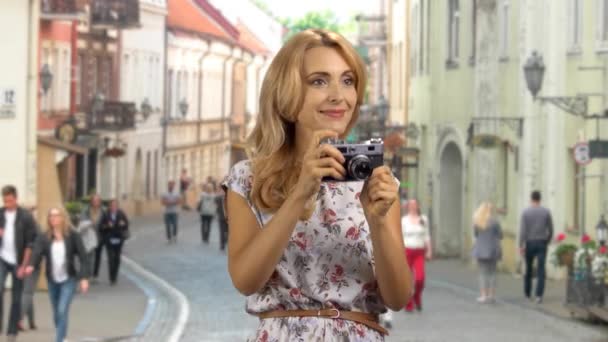Πορτρέτο μιας χαρούμενης ξανθιάς τουρίστριας που βγάζει φωτογραφίες σε ευρωπαϊκό δρόμο. Vintage ρετρό φωτογραφική μηχανή. - Πλάνα, βίντεο