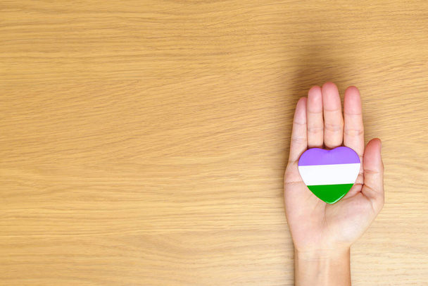 Queer Pride Day et LGBT pride month concept. main tenant pourpre, blanc et vert forme de coeur pour lesbiens, gais, bisexuels, transgenres, genderqueer et ansexuels communauté - Photo, image