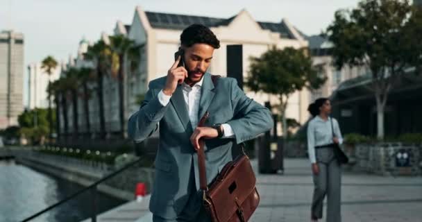 Businessman, walking and city with happiness and phone call for good news with briefcase for work. Male person, entrepreneur and smartphone for communication in Dubai and business conversation - Footage, Video