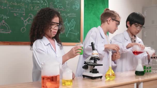 Kinderen die experimenteren in wetenschapsles terwijl ze op schoolbord staan in het laboratorium. Gelukkige student ontdekken en leren over biochemische vloeistof tijdens het inspecteren en mengen monster. Pedagogie. - Video