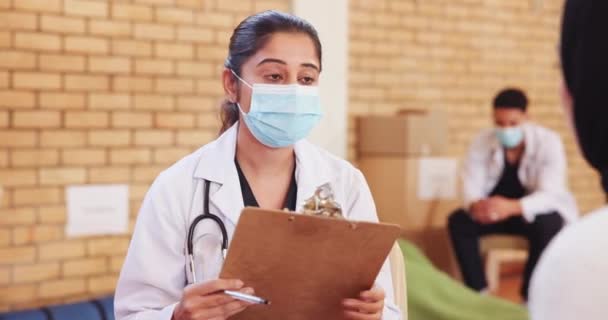 Doctor, patient and health outreach for community service with consultation, throat infection or clipboard. NGO, charity and woman in discussion for medical support or social responsibility with mask. - Footage, Video