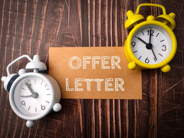 Top view clock and brown card with text OFFER LETTER on wooden background. - Photo, Image