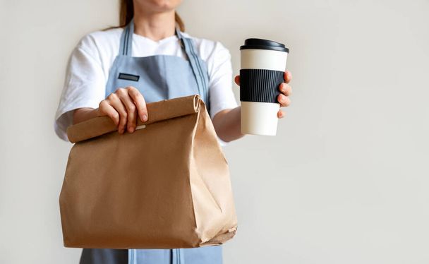 Concept de nourriture à emporter. Serveuse donnant tasse à café et sac en papier avec repas au client. - Photo, image