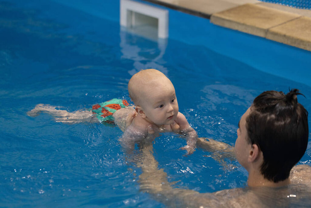 A baba érdeklődik az úszóedző iránt. Úszó edző kezében újszülött, tanítás úszni.  - Fotó, kép