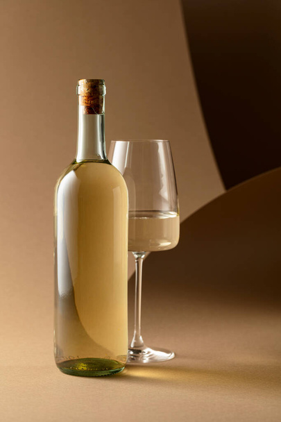 Flasche und Glas Weißwein auf beigem Hintergrund. - Foto, Bild