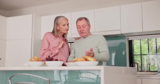 Mature couple, kitchen and food for diet, discussion and wellness for retirement health. Senior woman, man and croissant or muffin with fruit for breakfast, nutrition and elderly care or support. - Footage, Video